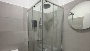 A modern bathroom with a glass-enclosed shower, a white toilet, and a wooden vanity with a sink. - Hostal Alcorcon (Alcorcón)