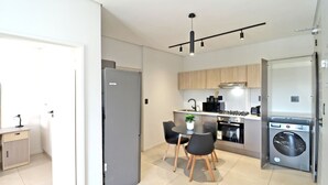 A modern kitchen with a dining area, a built-in washer, and a small table with chairs.