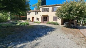 A two-story house with a gravel driveway and a covered patio area.