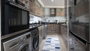 A modern kitchen with stainless steel appliances, wooden cabinets, and a central island.