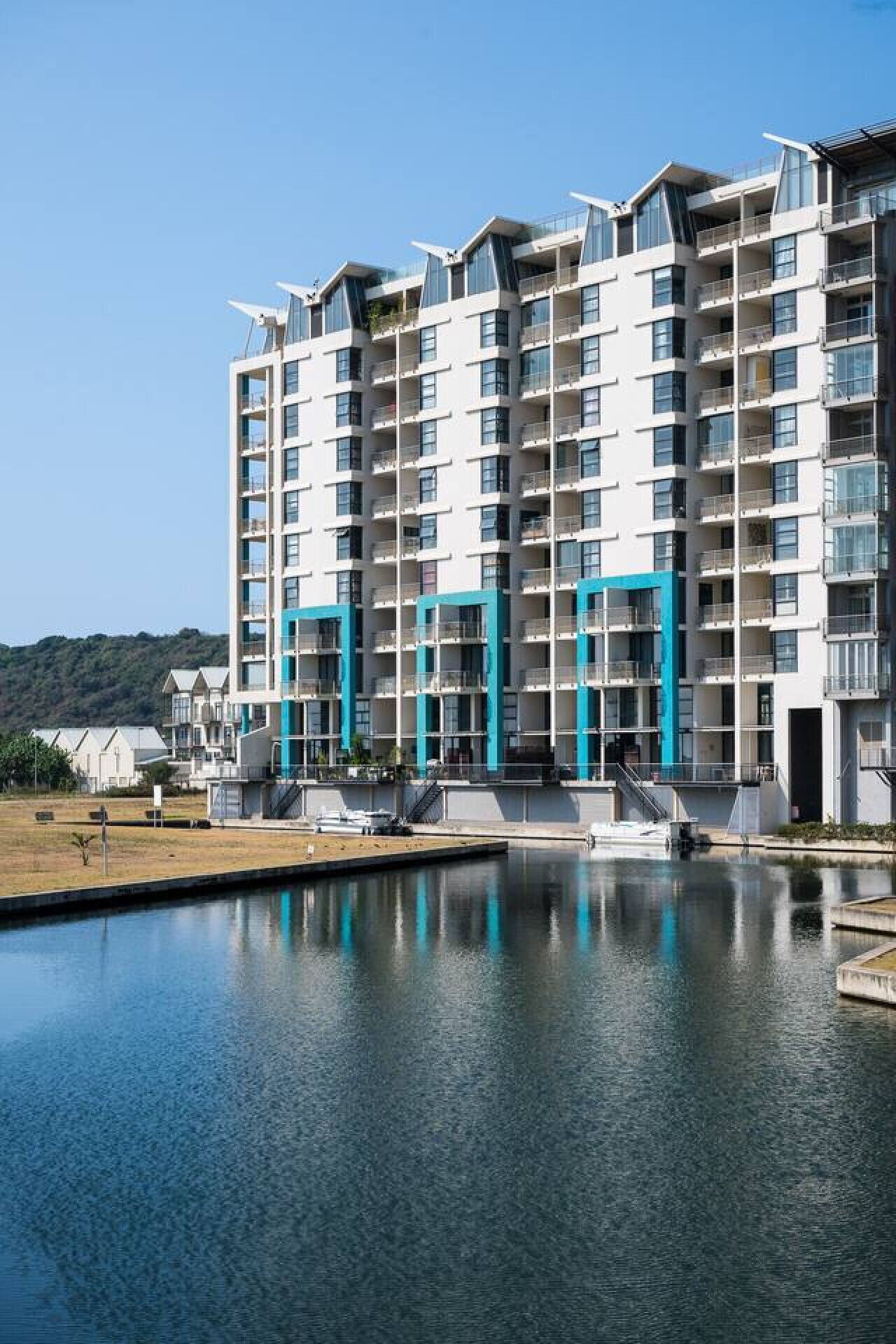 Un immeuble résidentiel à plusieurs étages, doté de balcons, avec une piscine à l’avant et un ciel dégagé.