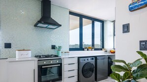 Eine moderne Küche mit Gasherd, Backofen und Waschmaschine, einem großen Fenster und Blick auf die Stadt.