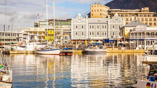 A harbor with boats docked, buildings with traditional architecture, and a mountain in the background. - 602 The Valour Luxurious Apartment (Cape Town)