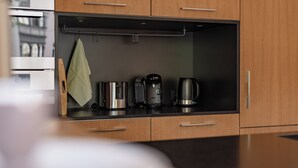 Una cocina moderna con armarios de madera, una cafetera de acero inoxidable y una tetera.