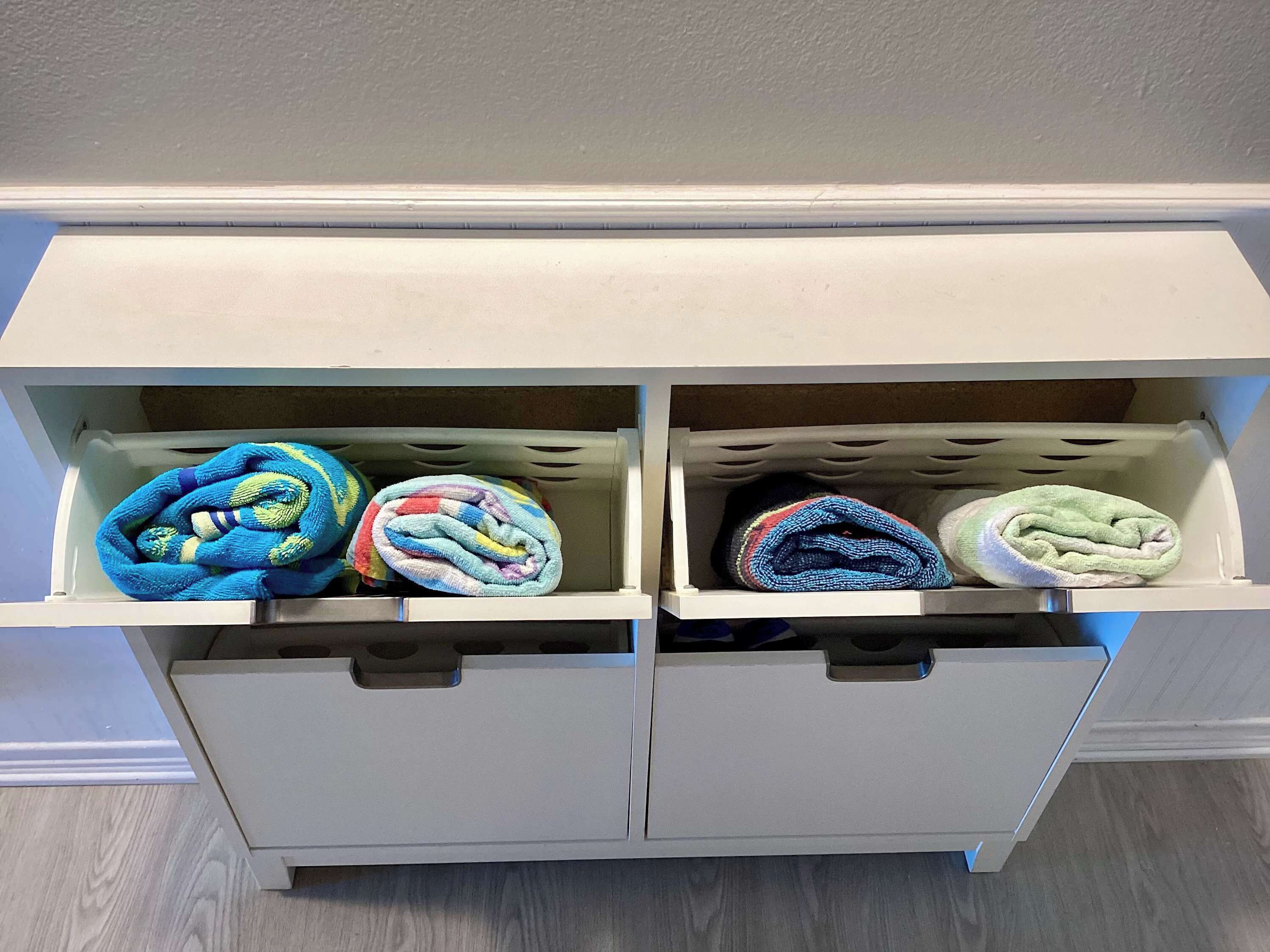 A storage unit with two compartments, each containing rolled towels in various colors.