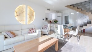 Een moderne woonkamer met een witte bank, een houten salontafel en een groot, rond kunstwerk aan de muur.