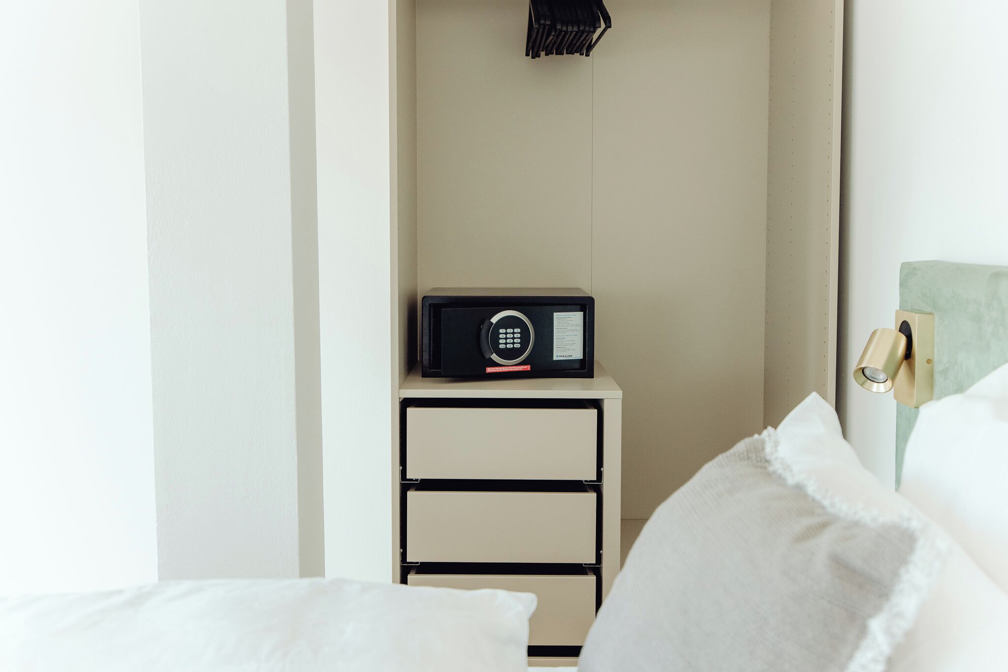 Une chambre d’hôtel avec un lit, une table de chevet avec une radio et une lampe fixée au mur.