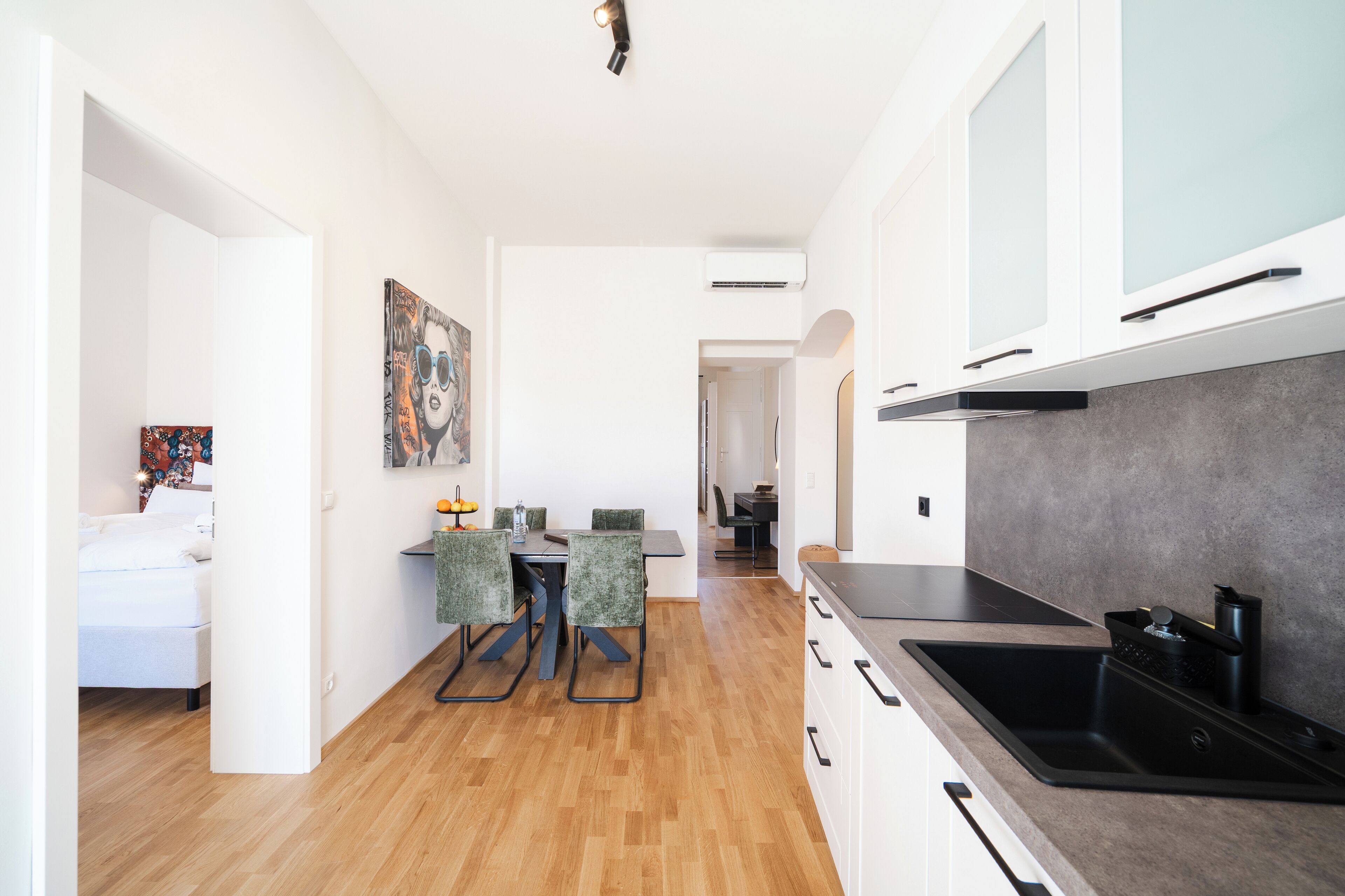 Eine moderne Küche mit einem großen, schwarzen Spülbecken, weißen Schränken und einem Essbereich mit Tisch und Stühlen.