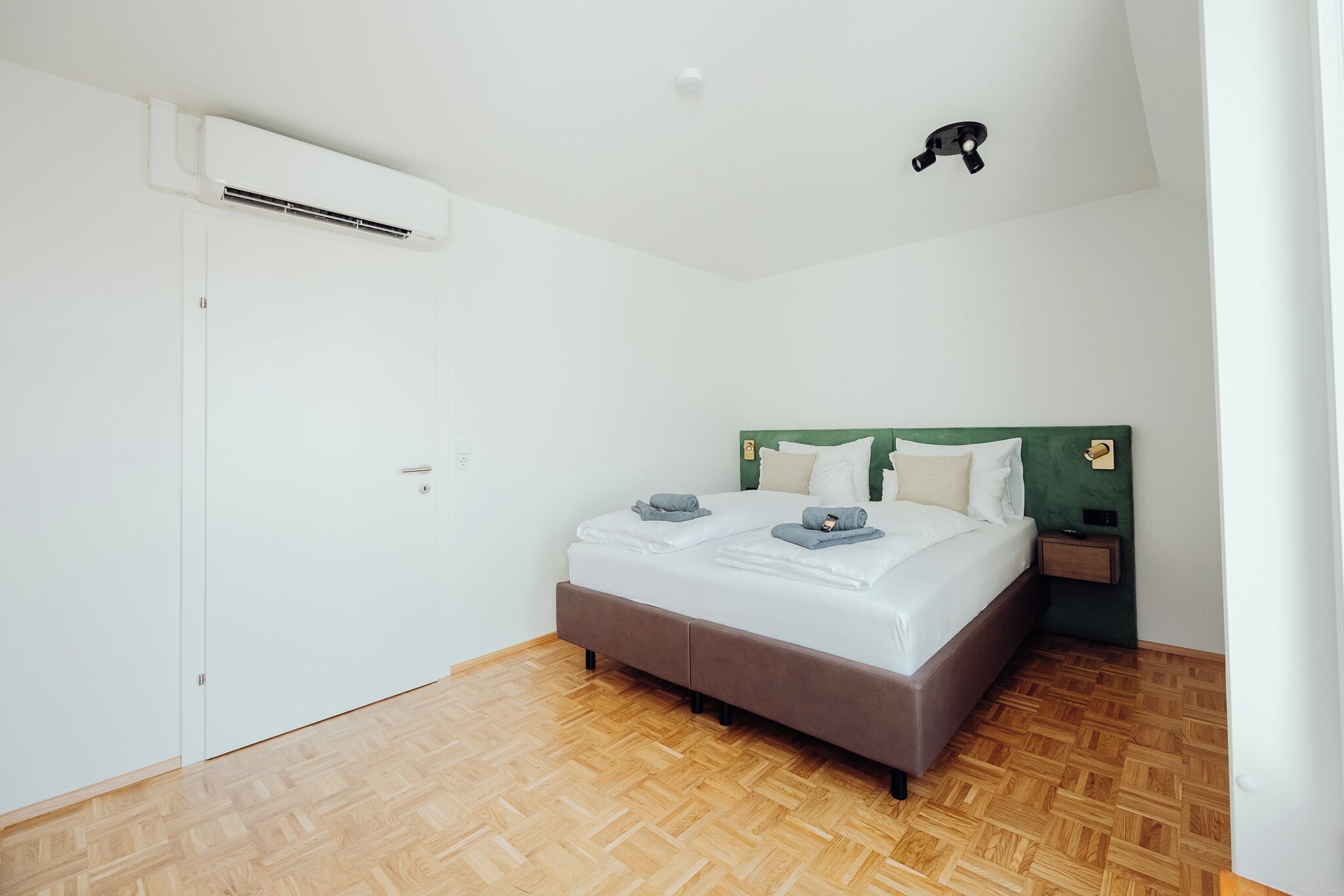 Une chambre à coucher comprenant un lit, une table de chevet et un appareil de climatisation.