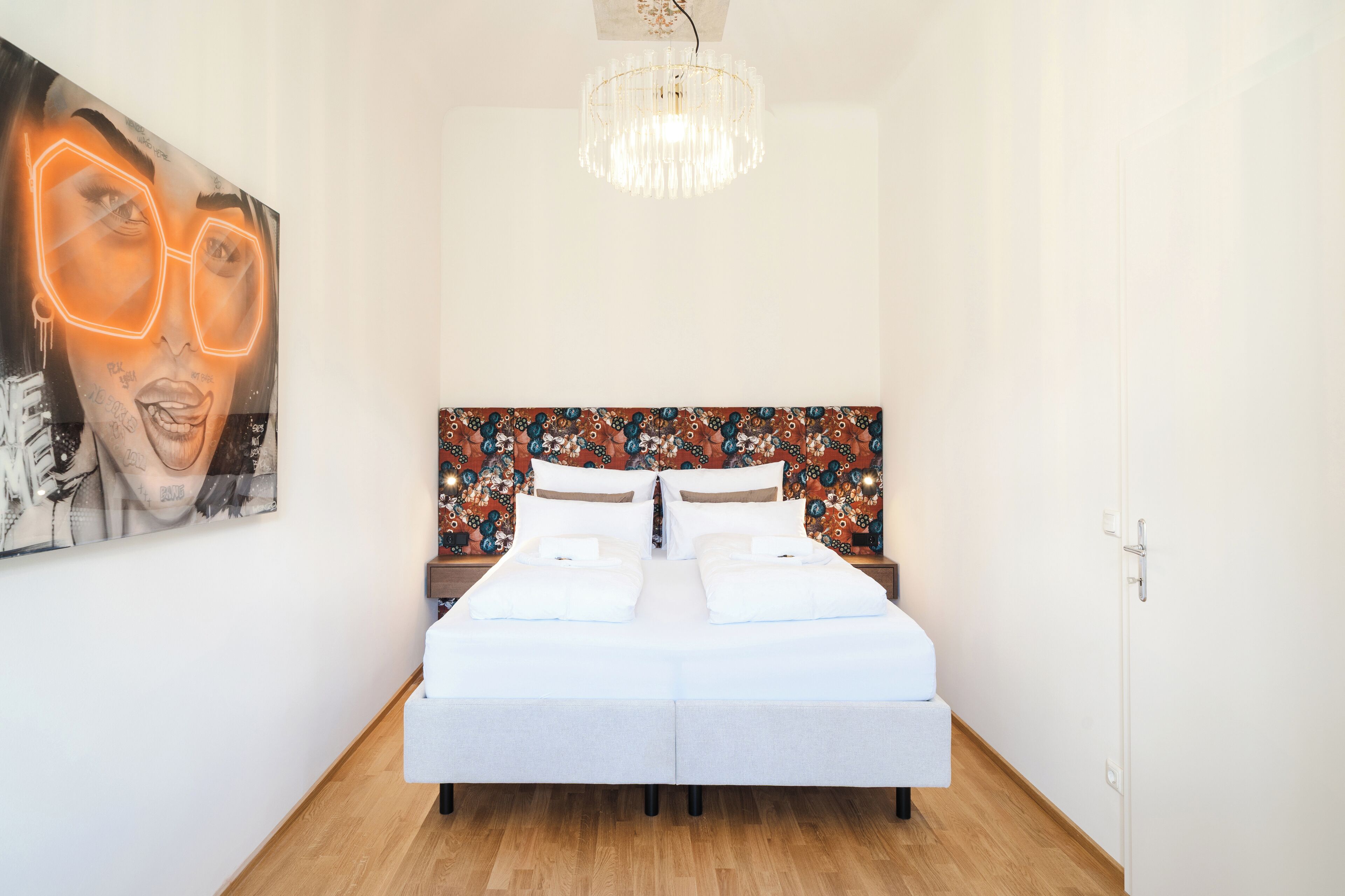 Une chambre à coucher avec un lit, un lustre et une tête de lit colorée.