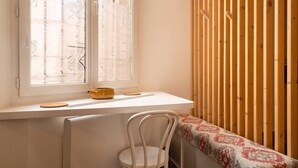 Una habitación con ventana, radiador, una silla y un panel de pared de listones de madera.