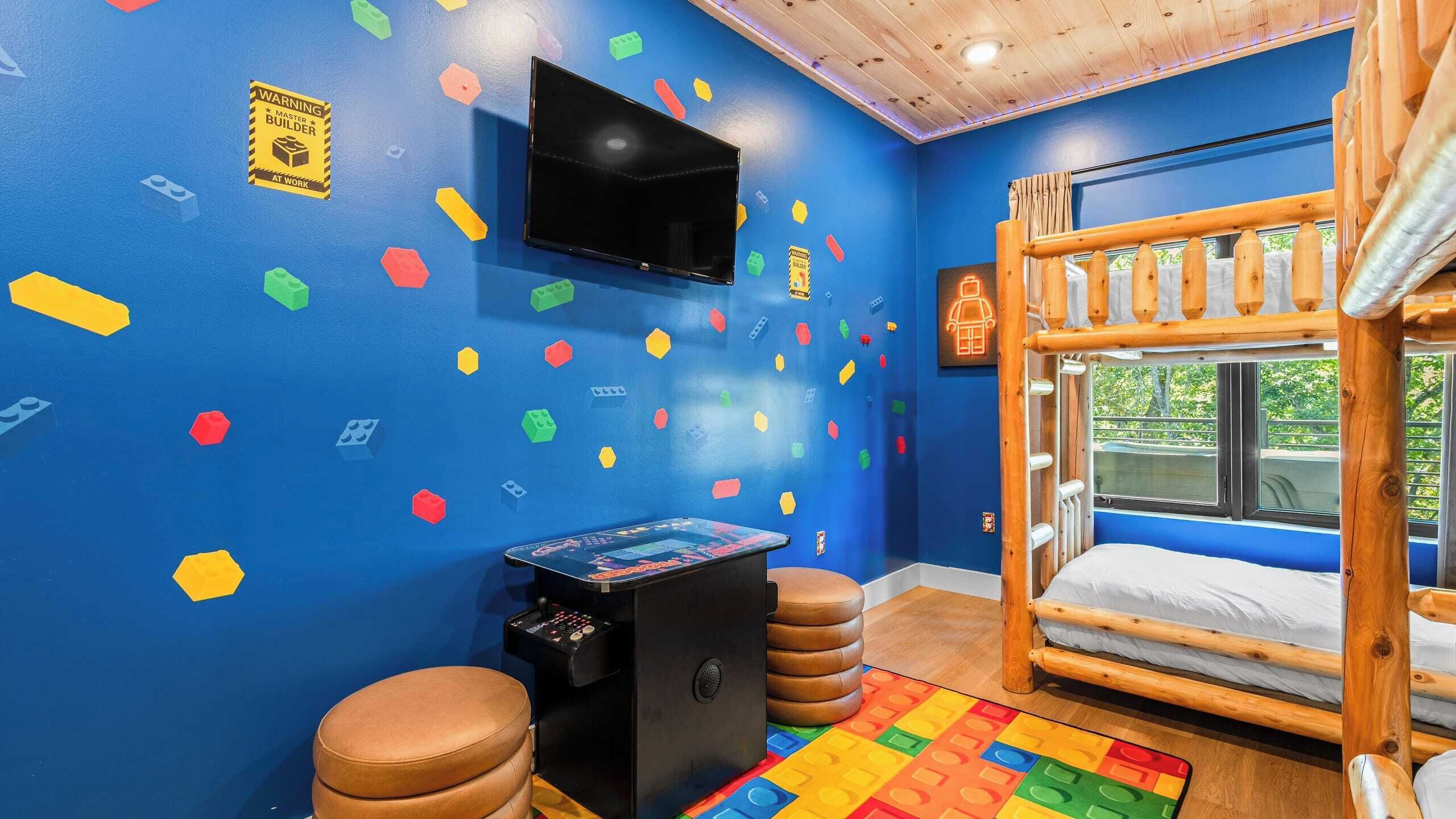 Um quarto com uma cama de solteiro, uma televisão presa na parede e decorações coloridas.