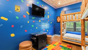 A room with a bunk bed, a television, a gaming console, and a wall decorated with colorful building blocks. - Ridgeview Retreat by Avantstay Sevierville Retreat Indoor Pool + Hot Tub + Firepit + Gym (Sevierville)