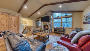 A cozy living room with a stone fireplace, leather sofas, and a wooden staircase. - Cozy Tahoe Retreat w/ Hot Tub, Movie Room & Forest Views 10th ave 2 by Avantstay (Tahoma)