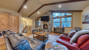 A cozy living room with a stone fireplace, leather sofas, and a wooden staircase.