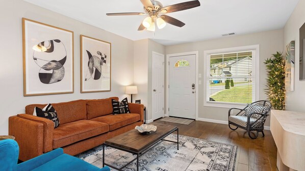 A living room with a sofa, coffee table, and a ceiling fan.