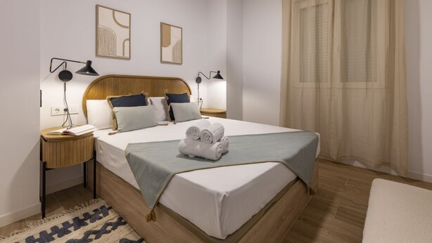 Une chambre à coucher bien aménagée, avec un grand lit, des lampes de chevet et deux œuvres d’art accrochées au mur.