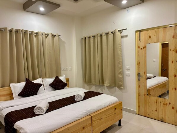 Un lit double avec un cadre en bois, des rideaux beiges et un miroir sur la porte.