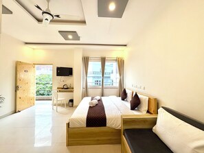 Une chambre d’hôtel avec un lit, un bureau, une télévision et une fenêtre avec des rideaux.