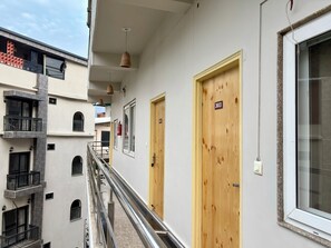 Un immeuble à plusieurs étages, doté de balcons, de portes en bois et d’une rambarde en métal.