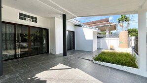 A modern house with a covered patio, a glass door entrance, and a small garden area. - Baiyok Villas Near Kathu Waterfall (Kathu)