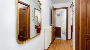 A hallway with a large mirror, wooden doors, and a radiator. - Casa Daisy 2 by Rentbeat  (Limone)