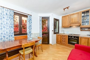 A kitchen with wooden cabinets, a dining table with chairs, and a red sofa.