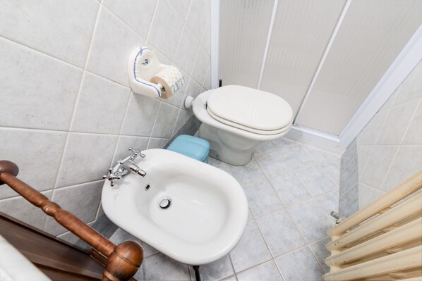 A bathroom with a bidet, toilet, and wooden bidet seat.