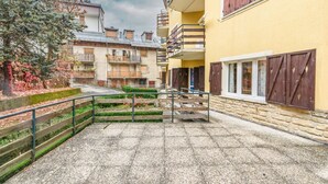 A courtyard with stone steps, a metal railing, and a building with wooden shutters and balconies. - Casa Daisy 2 by Rentbeat  (Limone)