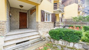 A residential building with a stone facade, wooden door, and steps leading to a balcony. - Casa Daisy 2 by Rentbeat  (Limone)