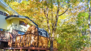 A building with a large wooden structure on a deck, surrounded by trees with autumn foliage. - rinne 2nd living Sauna Villa Nasu (Nasu)