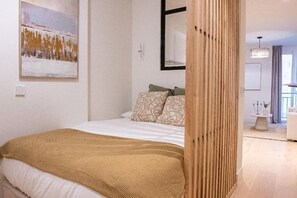 Ein Schlafzimmer mit einem Bett, Kissen, einer Decke, einem Bild an der Wand und einer Holzwand.