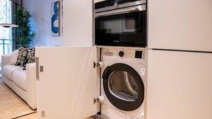 Ein kompakter Waschraum mit einer Waschmaschine mit Frontlader und einem eingebauten Backofen.