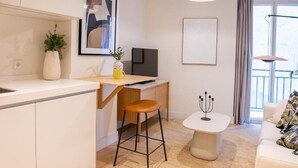 Eine moderne Küche mit weißer Arbeitsplatte, einem Holzschemel und einem kleinen weißen Tisch mit Kerzenhalter.
