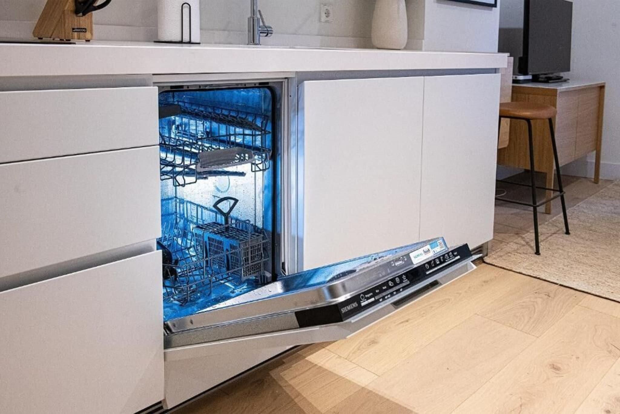 Een keuken met een inbouwvaatwasser, een houten aanrecht en een stoel.