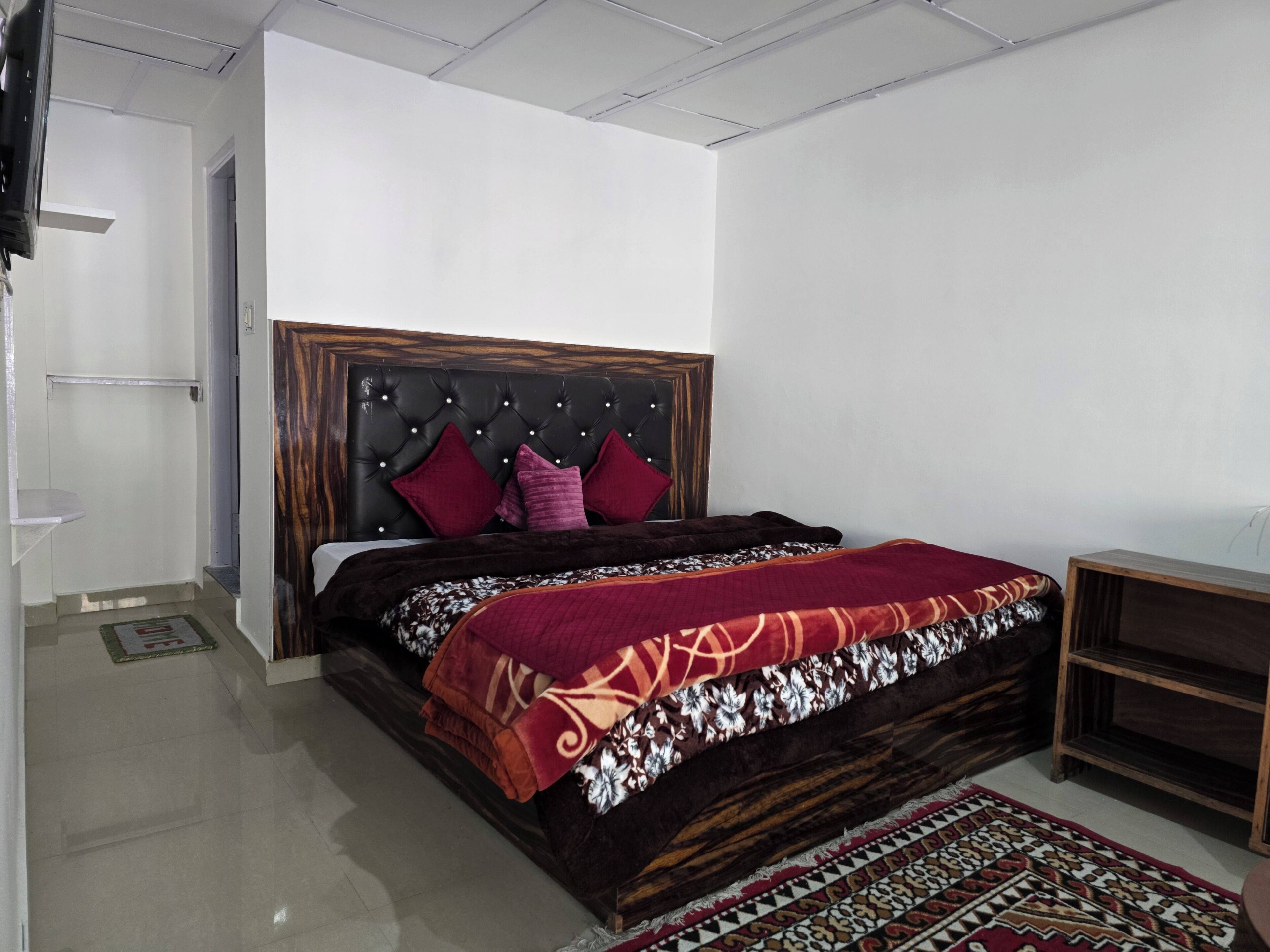 A bedroom with a bed, a headboard, a bedside table, and a rug.