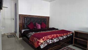 A bedroom with a bed, a headboard, a bedside table, and a rug.