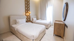 A hotel room with two beds, a wooden nightstand, a mirror, and a wall-mounted light fixture.