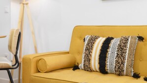 A yellow sofa with patterned cushions, a floor lamp, and a chair. - TH Peset Aleixandre 5D (Valencia)