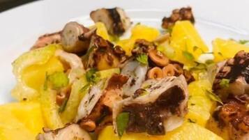 A plate of grilled octopus with lemon and herbs.