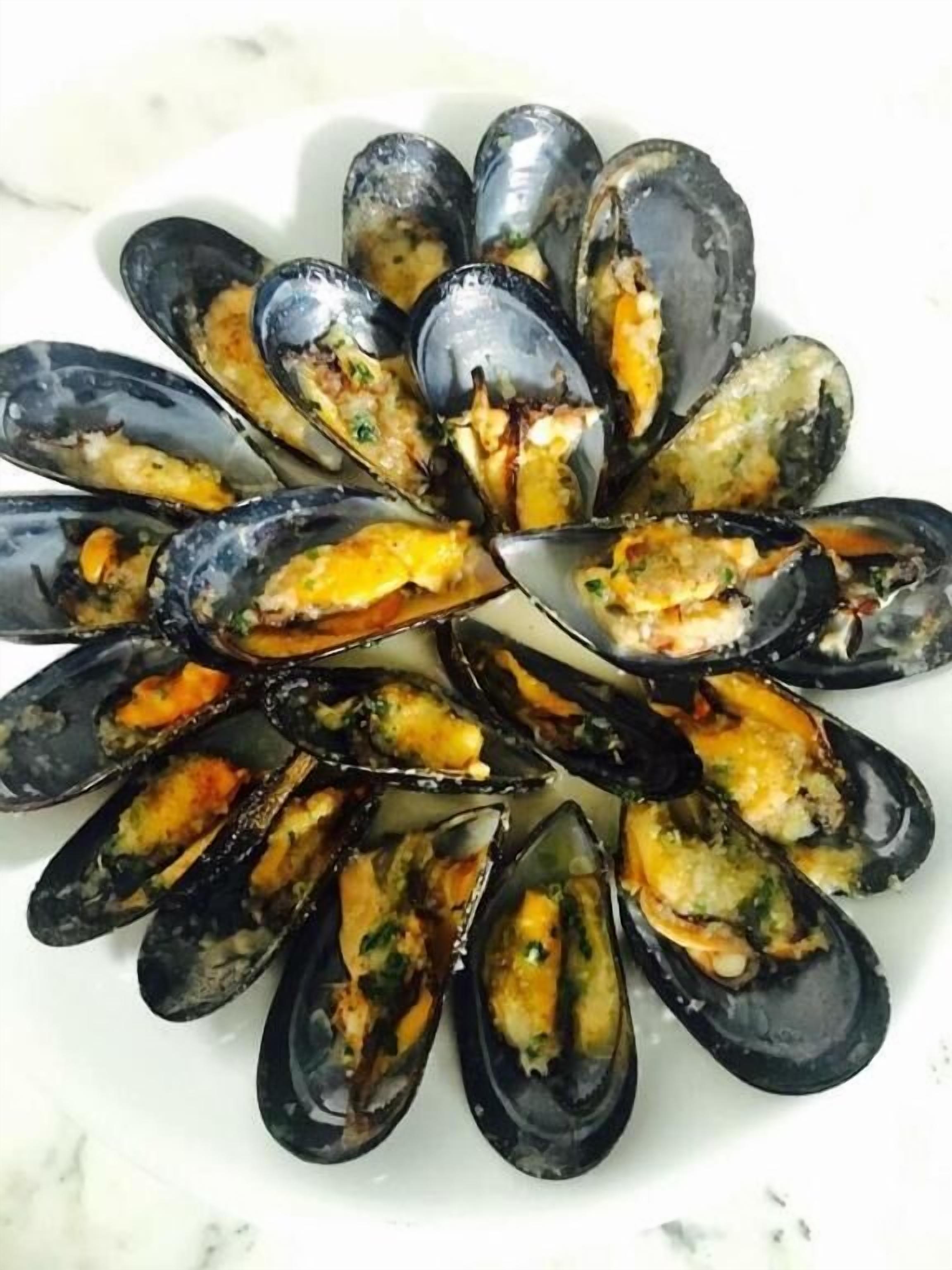 A plate of mussels with a golden crust, arranged in a circular pattern.