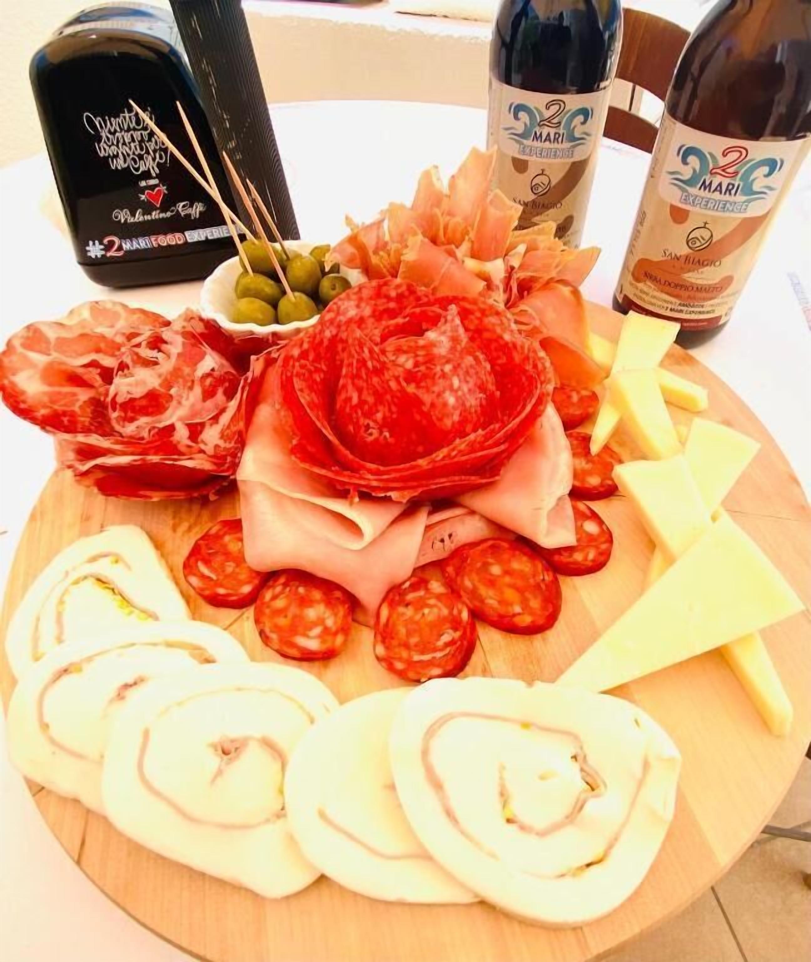 Una tabla de embutidos con diferentes carnes, quesos y aceitunas.