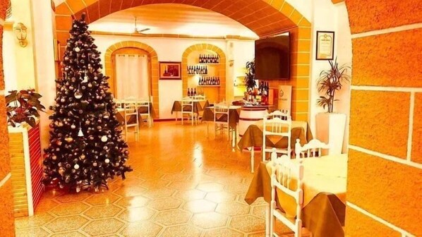 En hotellobby med en julgran, ett golv med hexagonalt mönster och en bardisk med flaskor.
