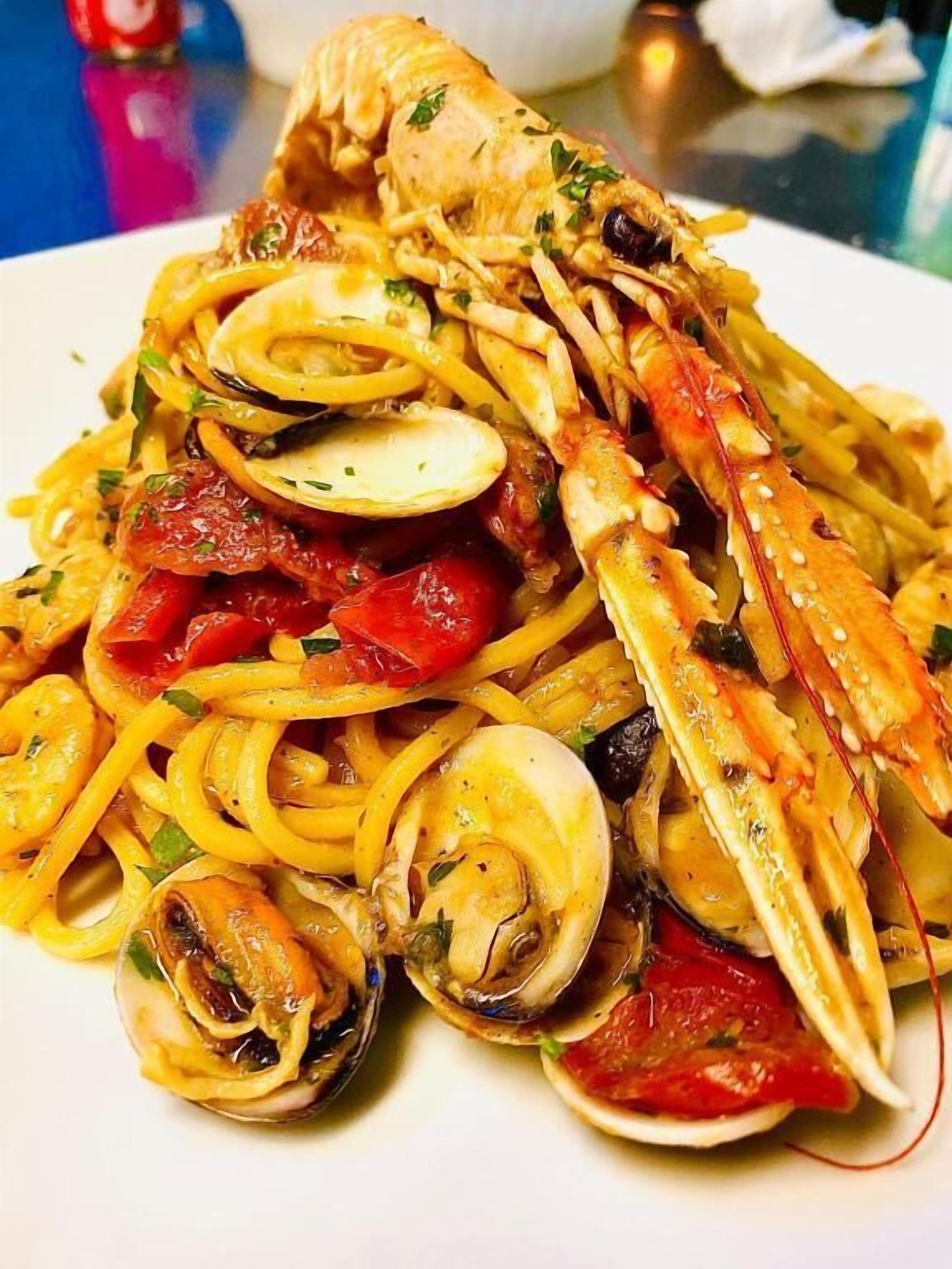 A seafood pasta dish with clams, mussels, and a lobster tail.