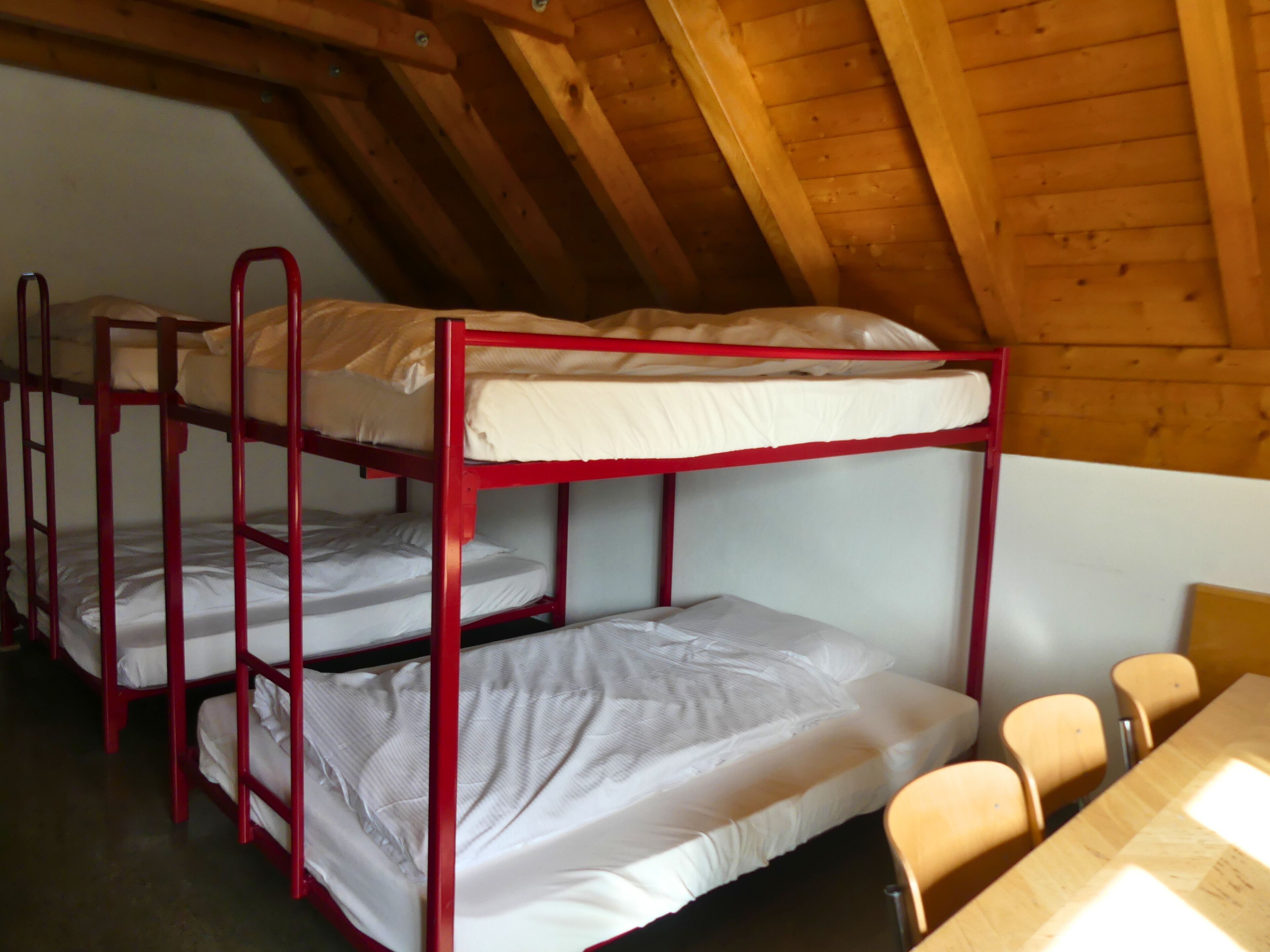 Ein Schlafsaalzimmer mit Etagenbetten und einem Holztisch.