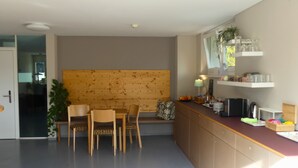 Une cuisine moderne avec des meubles en bois, une table à manger avec des chaises et une tête de lit en bois intégrée.