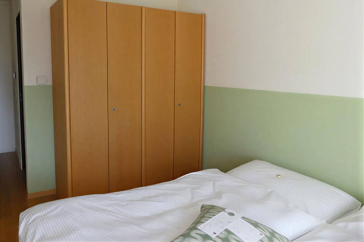 Un dormitorio con cama, un armario de madera y pared verde y blanca.