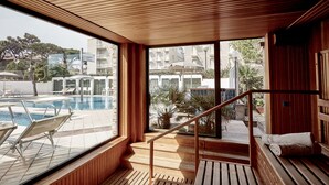 Interior de madera con vista a la piscina, escalones de madera y un banco con toallas.