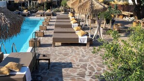 Un área junto a la piscina con sillones de descanso y una terraza de piedra.