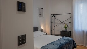 A modern bedroom with a bed, bedside table, and a wall-mounted control panel. - Cosy is a very cozy modern facility in soft colors, center of Bari (Bari)